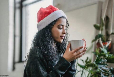 A girl holding a cup wearing christmas cap