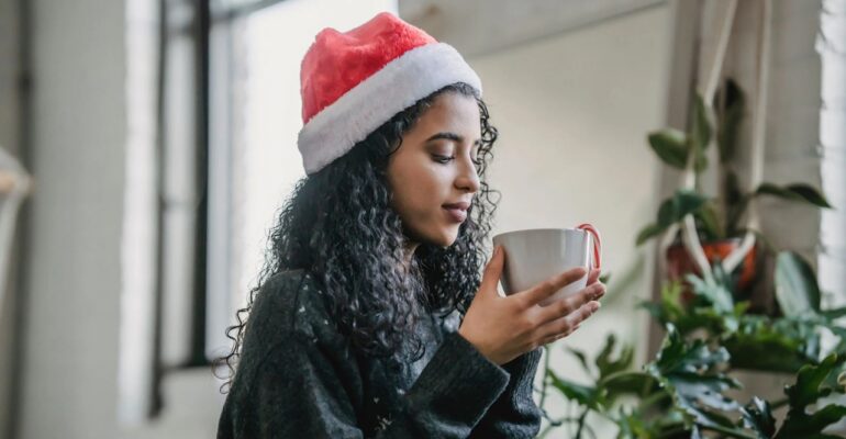 A girl holding a cup wearing christmas cap