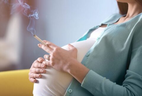 Pregnant woman holding a cigarette, representing the risks of smoking during pregnancy