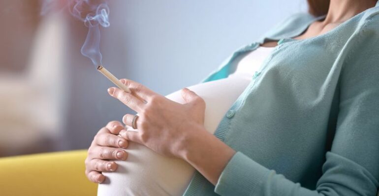 Pregnant woman holding a cigarette, representing the risks of smoking during pregnancy