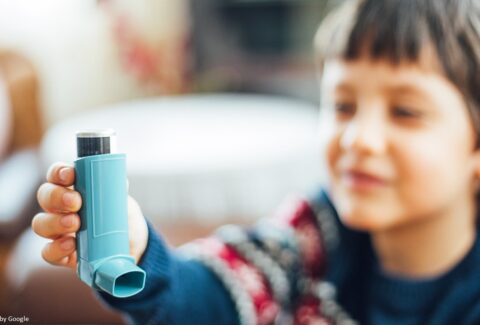 Image of a young boy using an asthma inhaler to manage his asthma symptoms.
