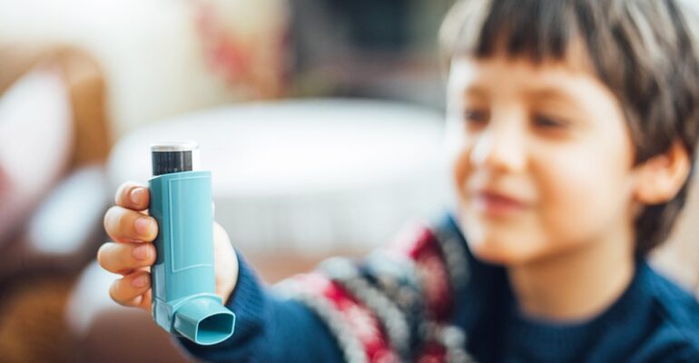 Image of a young boy using an asthma inhaler to manage his asthma symptoms.