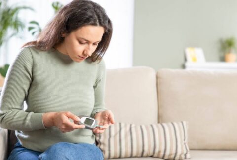 Image of a diabetic woman monitoring her blood sugar level with a glucometer