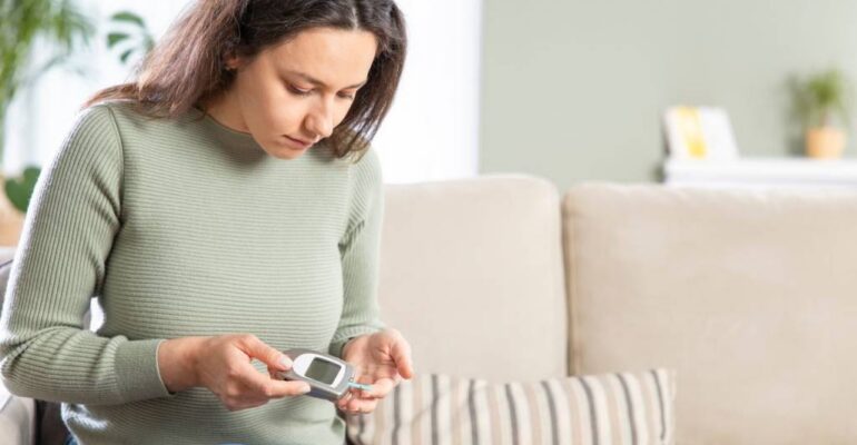 Image of a diabetic woman monitoring her blood sugar level with a glucometer