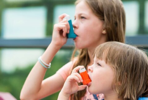 Image of person experiencing common asthma symptoms such as wheezing, shortness of breath, and coughing.