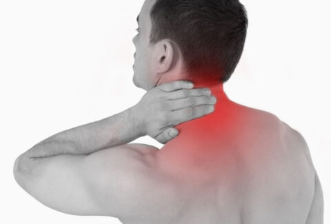 A person holding their neck and shoulder area with a pained expression on their face.