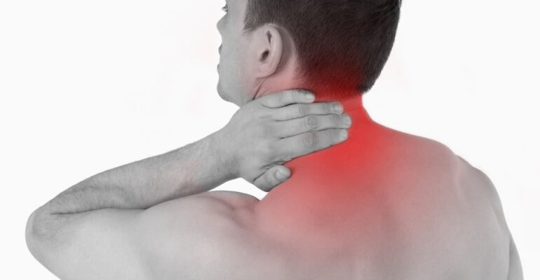 A person holding their neck and shoulder area with a pained expression on their face.