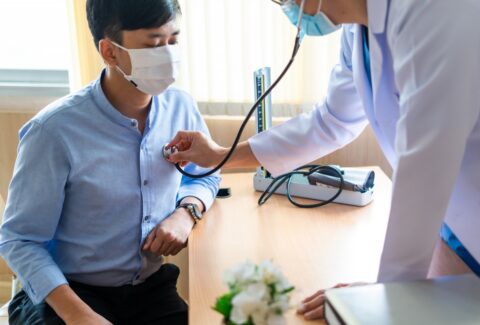 Men's health screening tests - A doctor examining a patient's blood pressure, cholesterol levels, and prostate gland.