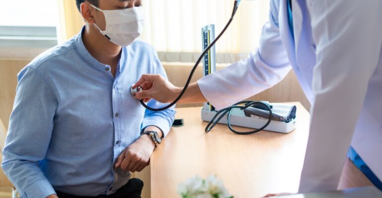 Men's health screening tests - A doctor examining a patient's blood pressure, cholesterol levels, and prostate gland.