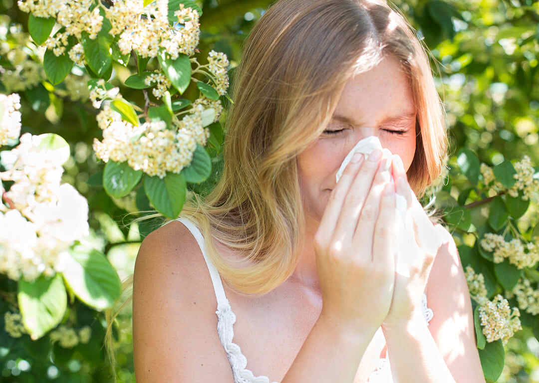 Image of a woman standing and sneezing