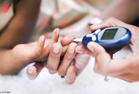 A hand checking other person diabetes with blood glucose meter