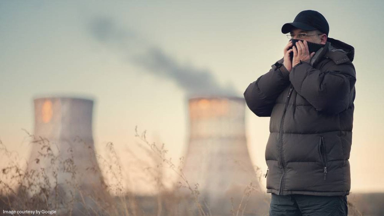 A person standing wear a mask near a power plant
